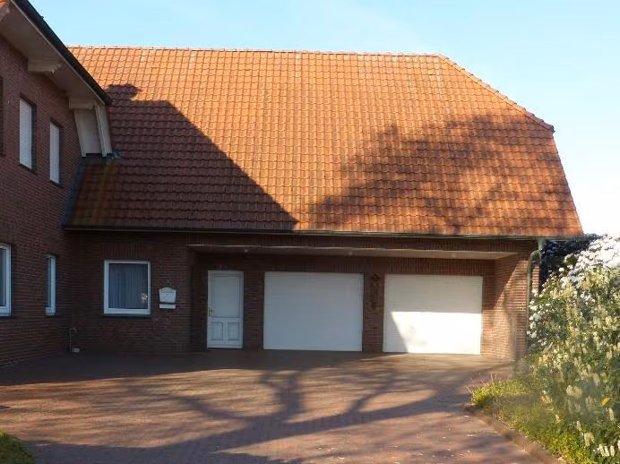 Zwangsversteigerung Einfamilienhaus in Dinklage – Nordöstliche Ansicht mit Garagentoren und gepflasterter Zufahrt.