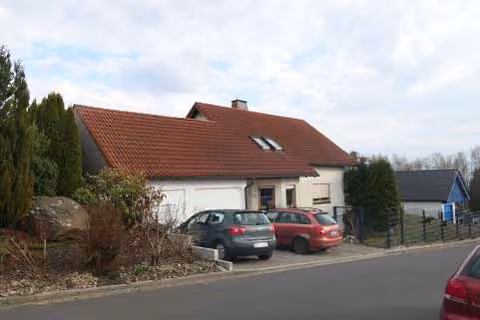 Zwangsversteigerung Einfamilienhaus in Selb, Selb-Plößberg – Straßenseitige Ansicht des Wohnhauses mit Vorgarten und Garage.