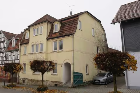 Zwangsversteigerung Mehrfamilienhaus in Bad Rodach – Blick von Nordosten auf die Straßen- und Giebelfassade des Dreifamilienhauses.