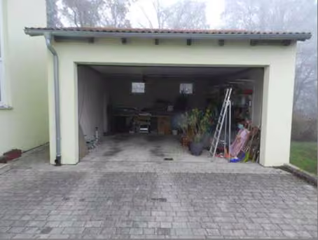 Zwangsversteigerung Einfamilienhaus in Parsberg – Doppelgarage von der Zufahrtsseite mit geöffnetem Sektionaltor.