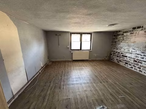 Zwangsversteigerung Einfamilienhaus in Siedenbollentin – Wohnzimmer im Erdgeschoss mit Dielenboden und verputzten Wänden.