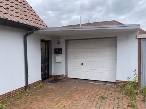 Zwangsversteigerung Einfamilienhaus in Wittmund, Carolinensiel – Massives Nebengebäude mit Garage und Zufahrt.