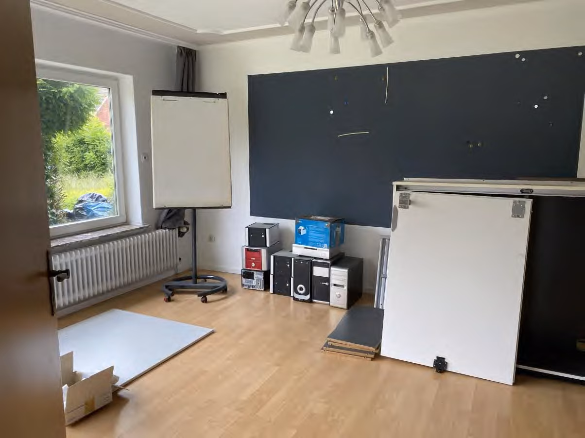 Zwangsversteigerung Einfamilienhaus in Wittmund, Carolinensiel – Wohnzimmer im Erdgeschoss mit Heizkörper und Fenster.