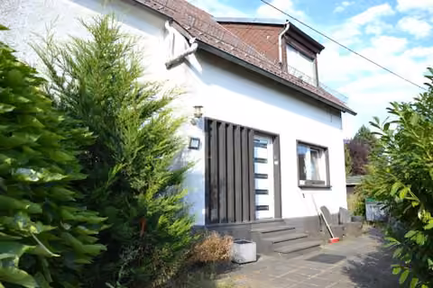 Zwangsversteigerung Einfamilienhaus in Ettringen – Straßen- und Hangansicht des Wohnhauses mit Vorgelände.