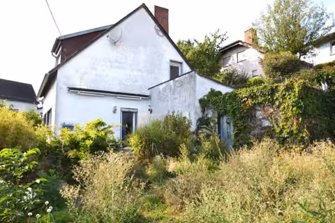 Zwangsversteigerung Einfamilienhaus in Ettringen – Gartenseitige Ansicht des Gebäudes mit Bewuchs.