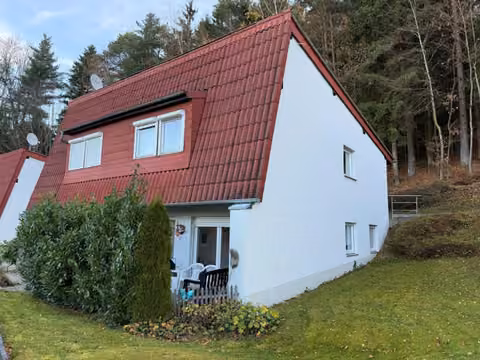 Zwangsversteigerung Eigentumswohnung in Neukirchen b. Hl. Blut, Mais-Kühberg – Außenansicht des Wohnhauses mit Vorgarten und Terrassenbereich.
