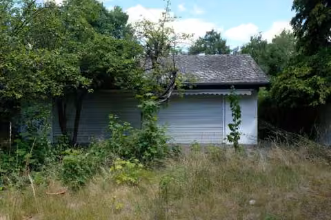 Zwangsversteigerung Einfamilienhaus in Berlin, Lichterfelde – Südfassade des Wohngebäudes mit überwachsenem Gartenbereich.