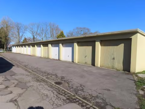 Zwangsversteigerung Grundstück in Alsdorf, Ofden – Schrägansicht der Garagenzeile mit Schwingtoren und Zufahrt.