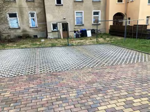 Zwangsversteigerung Eigentumswohnung in Burgstädt – Mit Gittersteinen befestigte Stellplatzfläche im Innenhof.