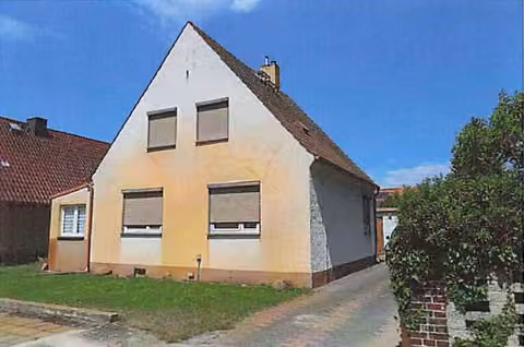 Zwangsversteigerung Wohn-/Geschäftshaus in Bad Liebenwerda – Straßenseitige Giebelansicht des Einfamilienhauses mit Vorgarten und Einfahrt.