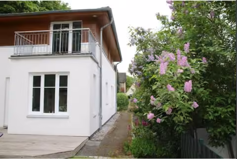 Zwangsversteigerung Einfamilienhaus in Hamburg, Niendorf – Seitenansicht mit Zuwegung und Blick auf den rückwärtigen Balkon.