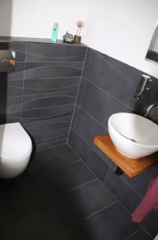 Zwangsversteigerung Einfamilienhaus in Hamburg, Niendorf – Gäste-WC im Erdgeschoss mit Sanitärobjekten und Wandfliesen.