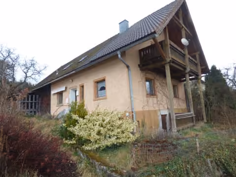 Zwangsversteigerung Einfamilienhaus in Teunz, Weiherhäusl – Südansicht des Wohnhauses mit angebautem Holzbalkon im Dachgeschoss.