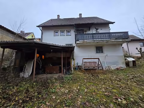 Zwangsversteigerung in Grub am Forst – Nordwestseite des Wohnhauses mit überdachtem Freisitz und Gartenfläche.