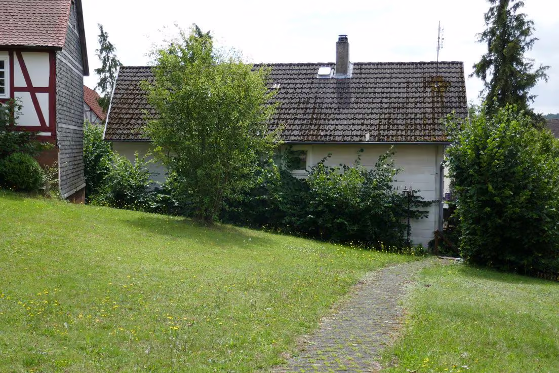 Zwangsversteigerung Einfamilienhaus in Münchhausen, Niederasphe – Nordansicht des Wohnhauses vom Nachbargrundstück aus.