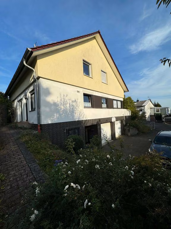 Zwangsversteigerung Einfamilienhaus in Marburg, Bauerbach – Südwestansicht mit Giebelseite und Garagenzufahrt.