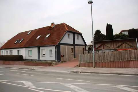 Zwangsversteigerung Einfamilienhaus in Dorf Mecklenburg – Blick von der Schweriner Straße auf Doppelhaushälfte und Unterstellschuppen