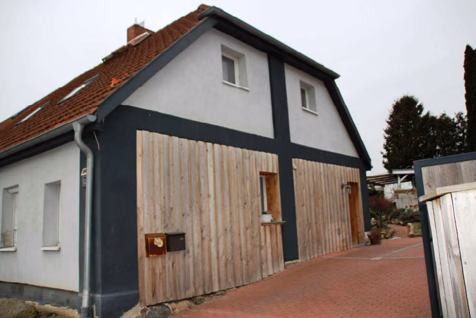 Zwangsversteigerung Einfamilienhaus in Dorf Mecklenburg – Giebelansicht der Doppelhaushälfte mit hofseitiger Holzverschalung