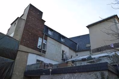 Zwangsversteigerung Wohn-/Geschäftshaus in Gladbeck, Stadtmitte – Rückansicht des Objekts mit Dachterrasse und Anbauten von der Ostseite.
