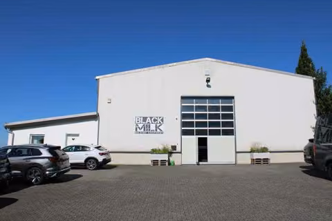 Zwangsversteigerung Büro in Freirachdorf – Süd-Ost-Ansicht der Lagerhalle mit gepflegter Grünfläche und Zufahrt.