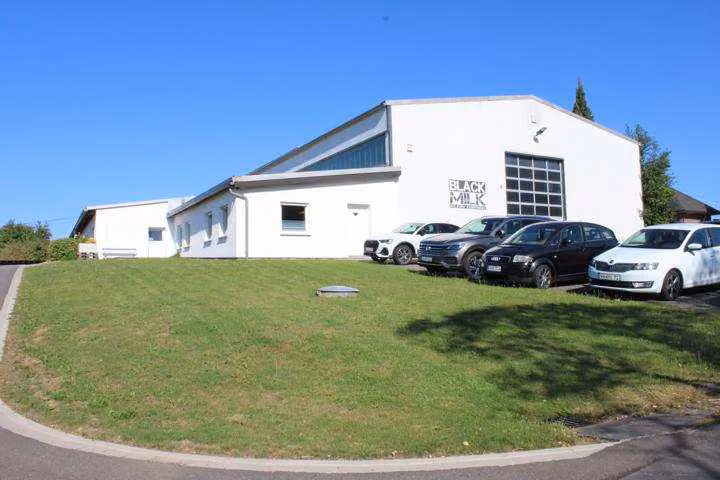 Zwangsversteigerung Büro in Freirachdorf – Ost-Ansicht der Lagerhalle mit Sektionaltor und Zufahrtsbereich.