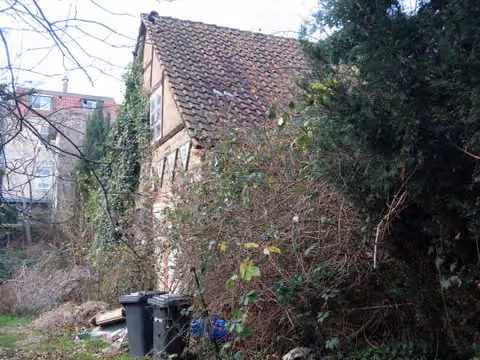 Zwangsversteigerung Einfamilienhaus in Blankenburg – Ansicht von Nordwest an der Straße mit Nebengebäude und Bewuchs.