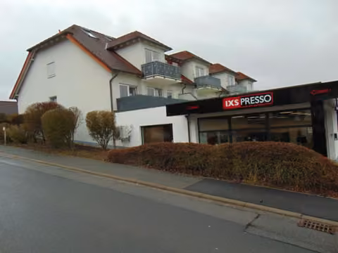 Zwangsversteigerung Eigentumswohnung in Hettstadt – Nord- und Ostseite des Wohn- und Geschäftshauses mit Balkonen.