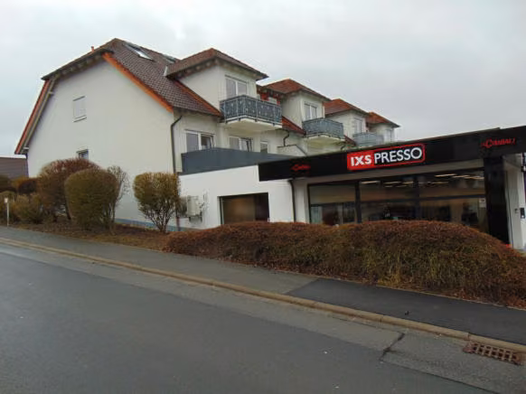 Zwangsversteigerung Eigentumswohnung in Hettstadt – Nord- und Ostseite des Wohn- und Geschäftshauses mit Balkonen.