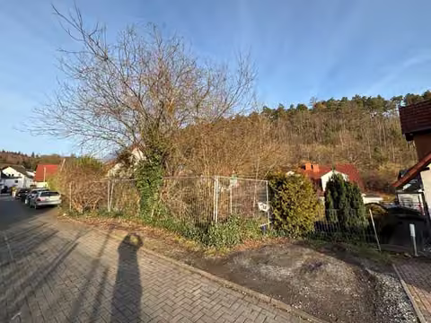 Zwangsversteigerung in Hemer, Becke – Straßenseitige Ansicht des Grundstücks mit Bauzaun und Bewuchs.