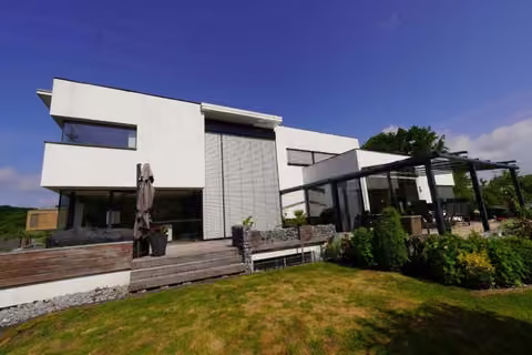Zwangsversteigerung Zweifamilienhaus in Bergkamen, Overberge – Ostansicht des Gebäudes mit Gartenbereich und überdachter Terrasse.