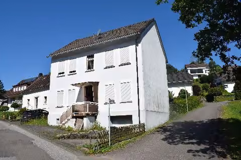 Zwangsversteigerung Einfamilienhaus in Attendorn, Lichtringhausen – Vorderansicht des freistehenden Einfamilienhauses mit Straße und Zufahrt.
