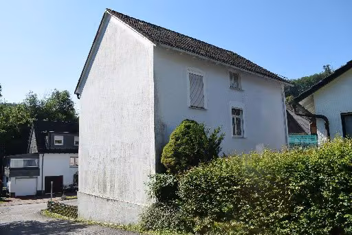 Zwangsversteigerung Einfamilienhaus in Attendorn, Lichtringhausen – Seitenansicht des Wohnhauses mit Kellergeschoss und Garageneinfahrt.