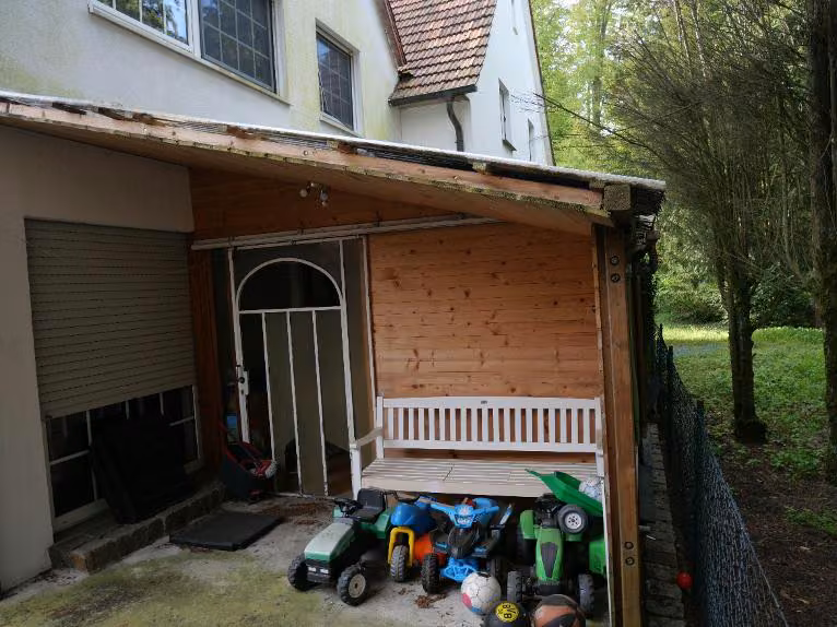 Zwangsversteigerung Doppelhaushälfte in Halle (Westf.), Hörste – Überdachte Holzterrasse auf der Rückseite des Hauses.