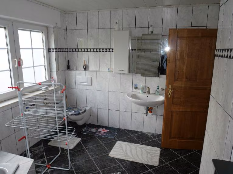 Zwangsversteigerung Doppelhaushälfte in Halle (Westf.), Hörste – Gefliestes Badezimmer im Obergeschoss mit Badewanne und Dusche.