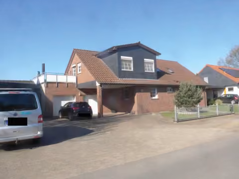 Zwangsversteigerung Eigentumswohnung in Petershagen, Südfelde – Vorderansicht des Zweifamilienhauses mit Zufahrt und Garagentrakt.