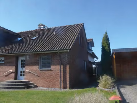 Zwangsversteigerung Eigentumswohnung in Petershagen, Südfelde – Seitenansicht des Wohnhauses mit Satteldach und Gartenfläche.