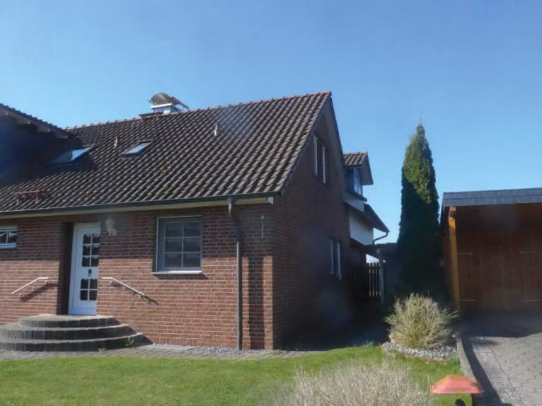 Zwangsversteigerung Eigentumswohnung in Petershagen, Südfelde – Seitenansicht des Wohnhauses mit Satteldach und Gartenfläche.