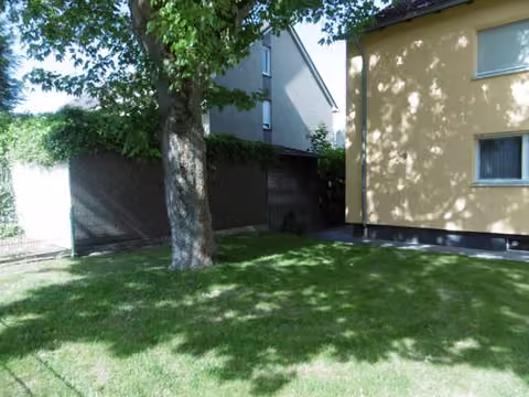 Zwangsversteigerung Reihenhaus in Herne, Wanne – Seitenansicht des Wohnhauses mit Rasenfläche und Baumbestand.