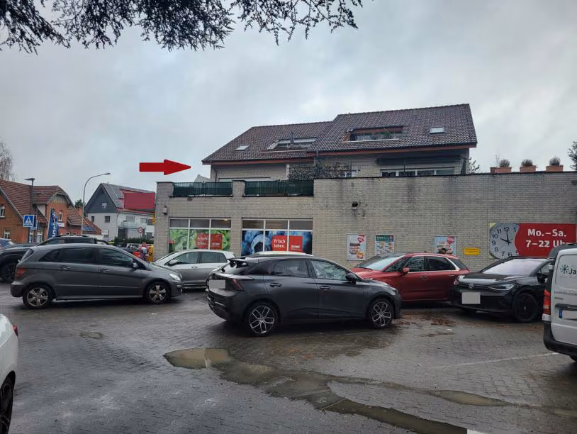 Zwangsversteigerung Eigentumswohnung in Paderborn, Schloß Neuhaus – Hoffläche auf dem Supermarkt mit Ansicht der Südseite des Wohngebäudes.