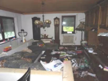 Zwangsversteigerung Einfamilienhaus in Gauting – Wohnzimmer im Erdgeschoss mit sichtbaren Ablagerungen und Verschmutzungen.