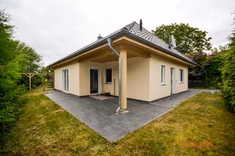 Zwangsversteigerung Einfamilienhaus in Gramzow, Lützlow – Schrägansicht des Walmdachbungalows mit gepflasterter Hofzufahrt und überdachtem Eingangsbereich.