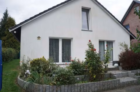 Zwangsversteigerung in Hamburg, Rahlstedt – Vorderansicht der Südseite des Einfamilienhauses mit Terrasse und Vorgarten.