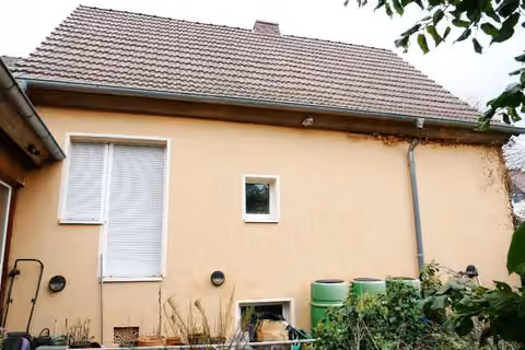 Zwangsversteigerung Einfamilienhaus in Kölleda, Beichlingen – Westfassade des Wohnhauses mit Fenstern und Hofbereich.