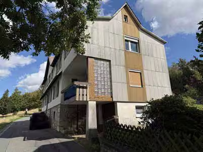Zwangsversteigerung Reihenhaus in Bad Steben, Bobengrün – Hauptansicht des Wohnhauses von Südosten mit Natursteinsockel und Garage