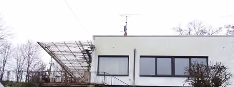 Zwangsversteigerung Einfamilienhaus in Motten – Nord-Ost-Ansicht des Wohnhauses mit Terrassenüberbau und Garagenzufahrt.