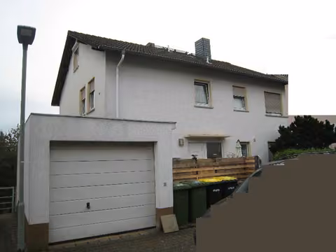 Zwangsversteigerung Mehrfamilienhaus in Büdingen – Straßenansicht des Mehrfamilienhauses mit angebauter Garage.