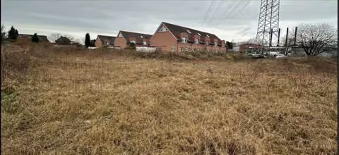 Zwangsversteigerung Grundstück in Voerde, Friedrichsfeld – Gesamtansicht des unbebauten Grundstücks mit Hochspannungsleitung im Hintergrund